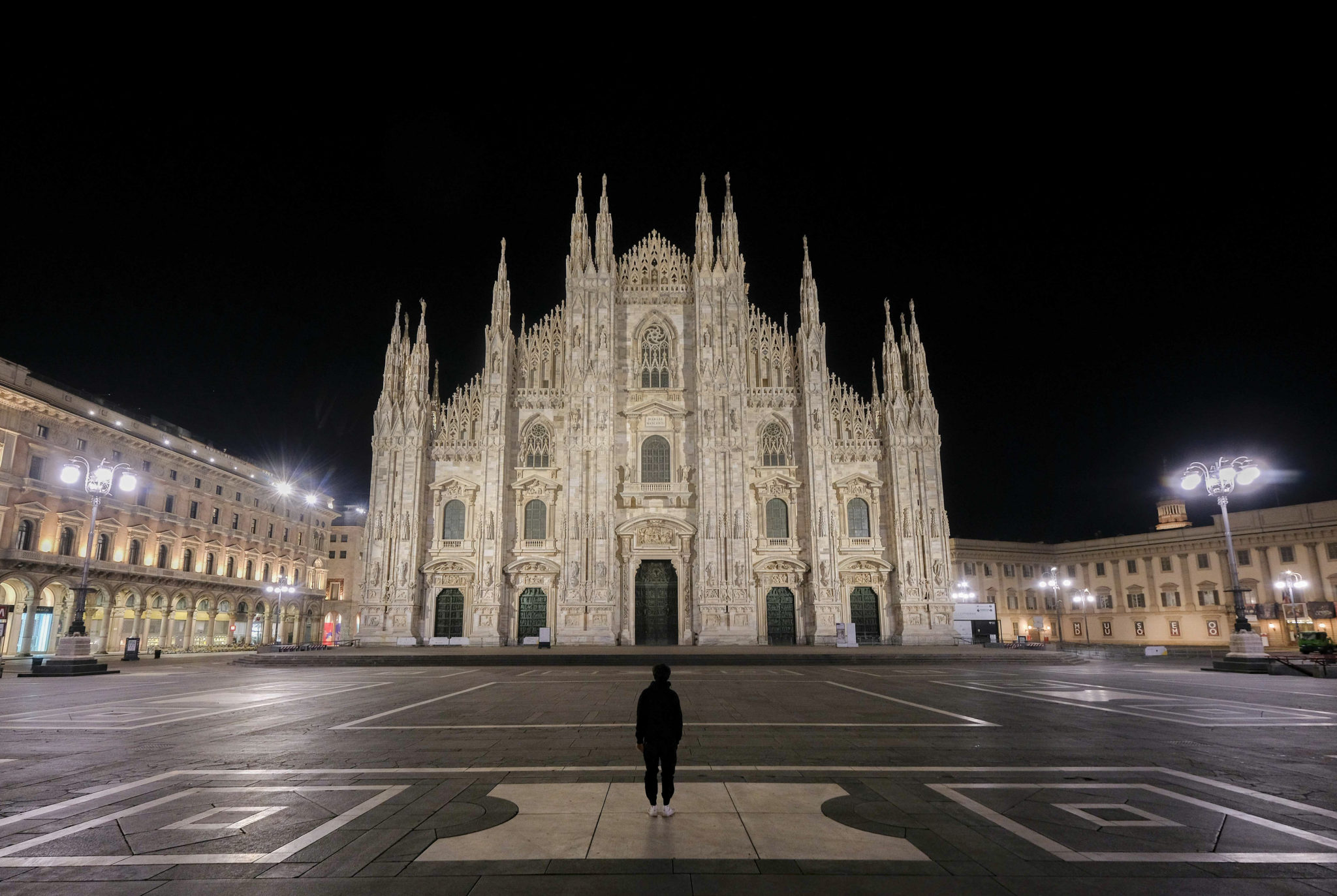 Un ragazzo osserva il duomo di Milano in una surreale piazza deserta ...